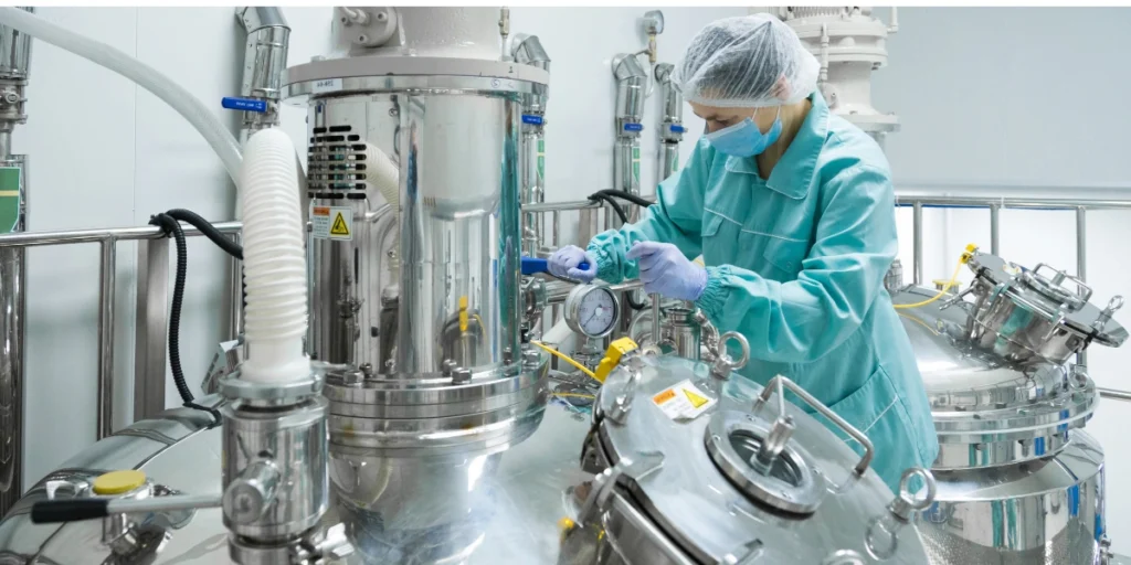 Technician monitoring stainless steel equipment in a third-party chemical manufacturing facility.