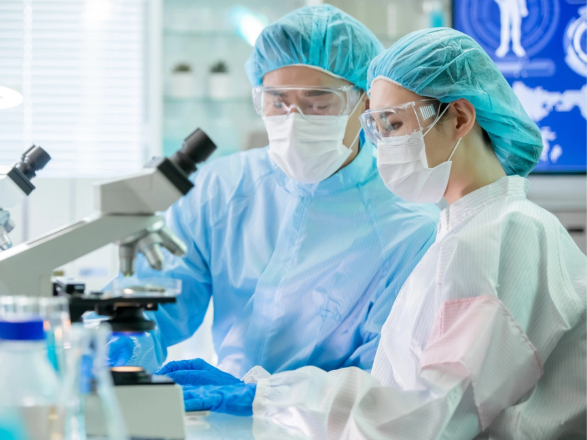 Laboratory professionals conducting microscope analysis as part of advanced chemical services in a controlled lab environment.