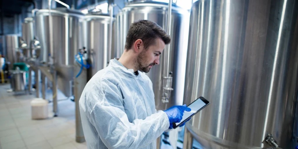 Third-Party Chemical Blending Pakistan worker using tablet to monitor production in modern industrial processing plant