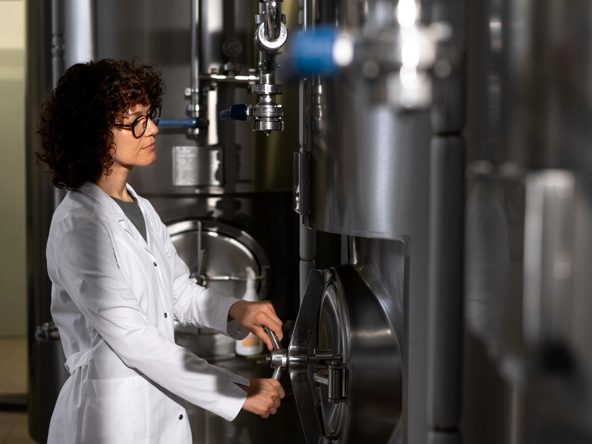 Custom Toll Manufacturing process with technician operating stainless steel industrial equipment in production facility